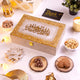 Noor Al-Lazeez Sweet Collection closed designer box with Arabic calligraphy, surrounded by festive treats like Kaju Katli, cookies, and dry fruits.