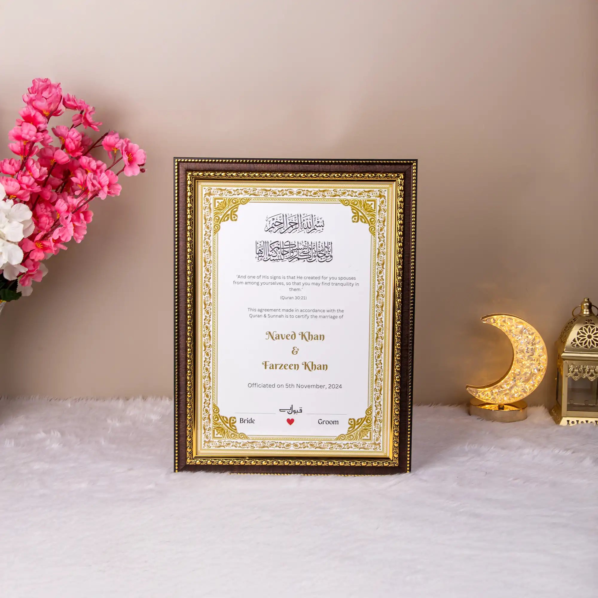 Divine Elegance Nikah Nama with Frame displayed on a white fur surface, featuring gold Islamic motifs and personalized names for a wedding gift. Main image