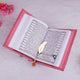 Open book with a pink cover and a gold feather on a light gray background