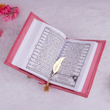 Open book with a pink cover and a gold feather on a light gray background