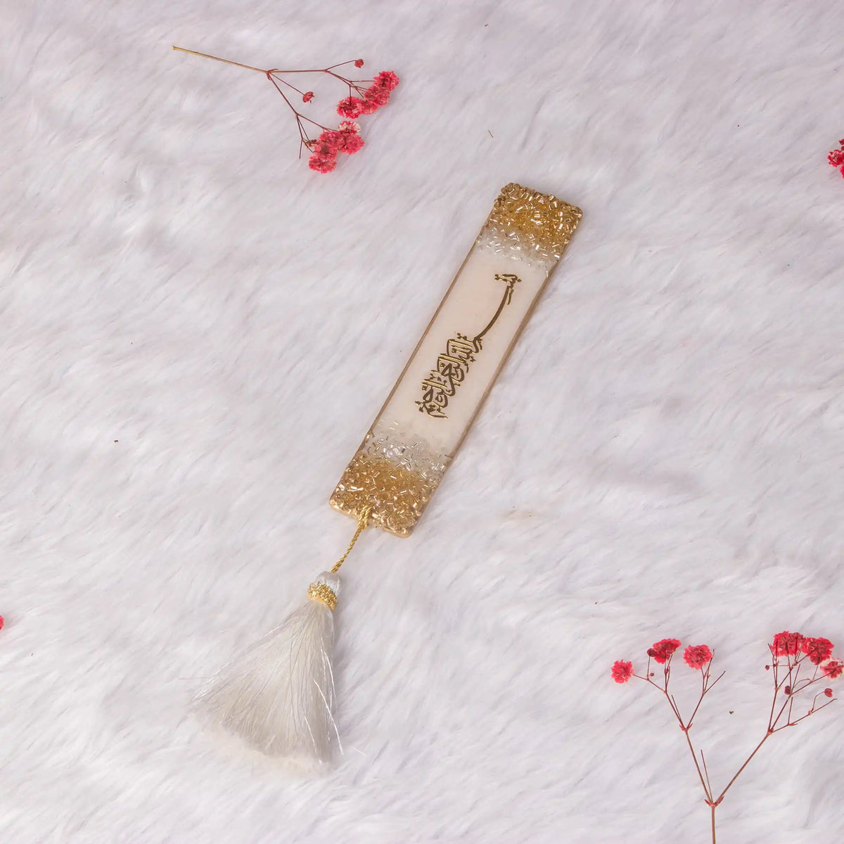 Offwhite Rehal Hamper bookmark with Arabic calligraphy, gold flakes, and white tassel on fur background. Elegant Quran gift accessory from Flakes Collection.