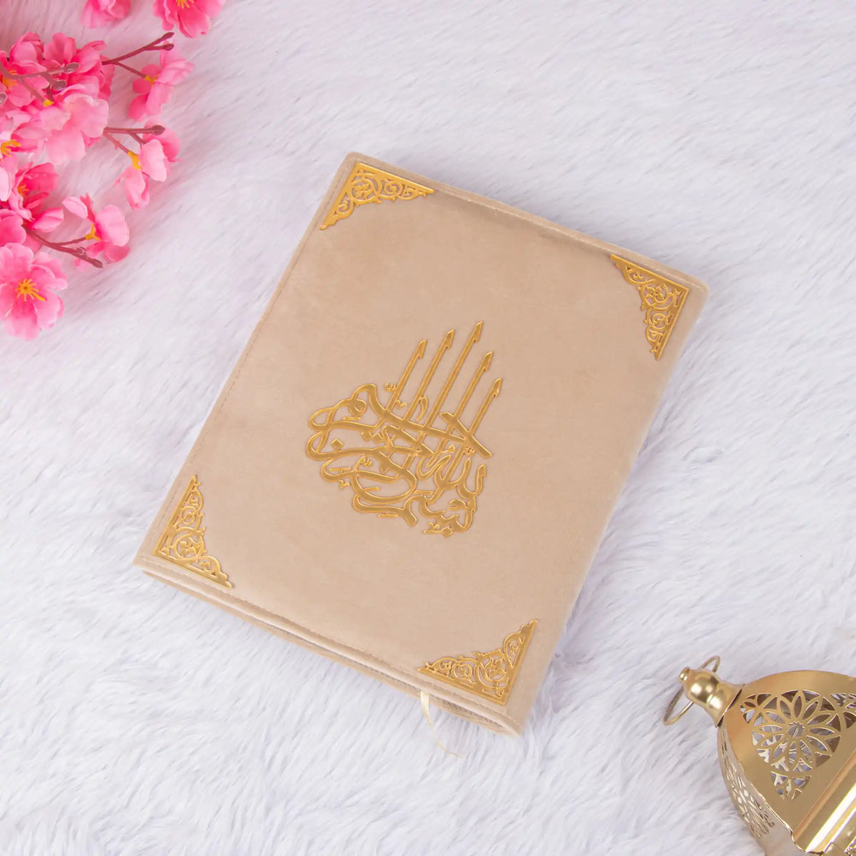 Cream-colored Kaaba Quran with gold calligraphy, laid flat with floral decor, a sophisticated and spiritual gift option.