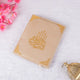 Cream-colored Kaaba Quran with gold calligraphy, laid flat with floral decor, a sophisticated and spiritual gift option.