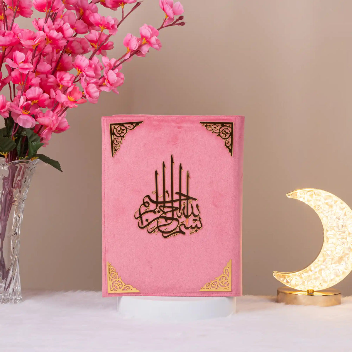 Pink velvet Kaaba Quran with black and gold detailing, upright with floral decor, a charming and personalizable Islamic gift.