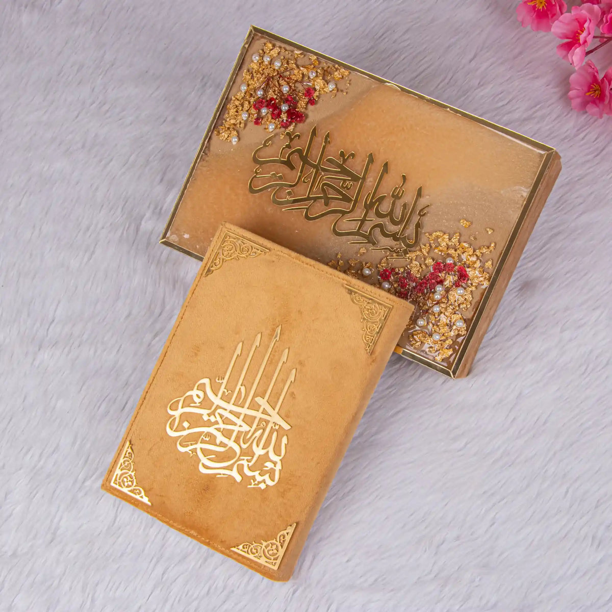 Decorative boxes with Arabic calligraphy on a light gray surface with pink flowers.
