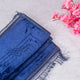 Blue towel with fringes on a light wooden surface with pink flowers.