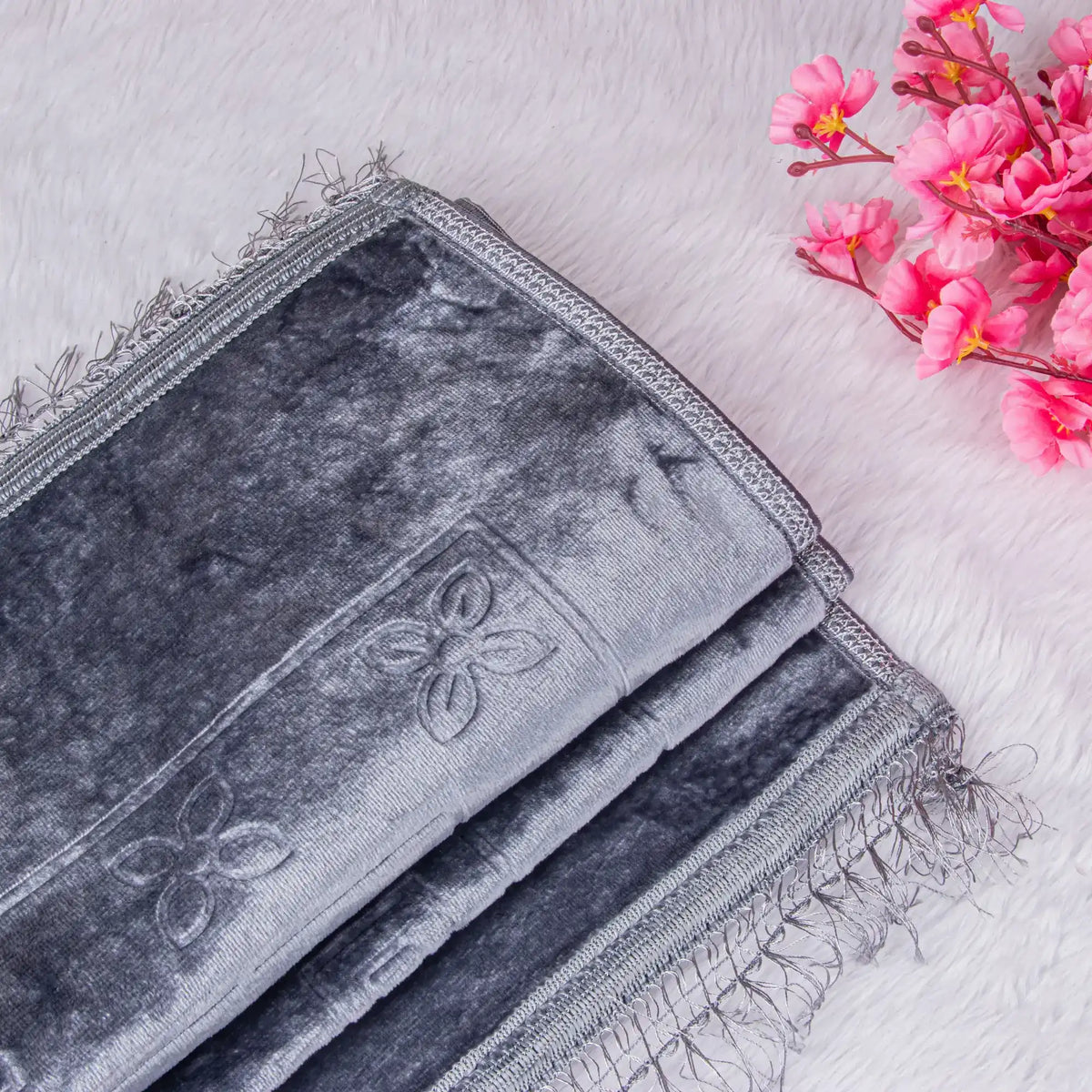 Gray embroidered fabric with pink flowers on a light wooden surface