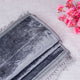 Gray embroidered fabric with pink flowers on a light wooden surface