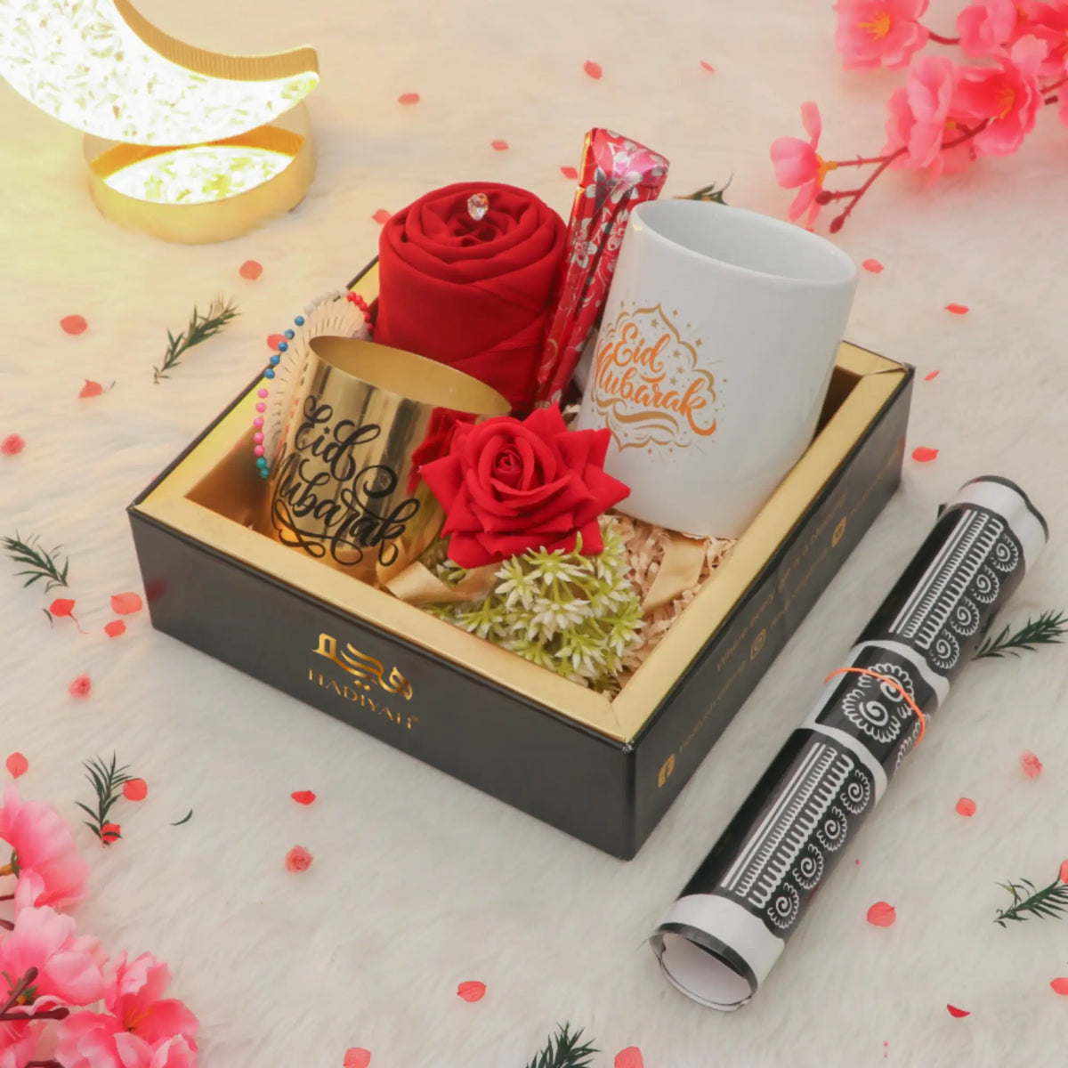 Gift set with red roses, a mug, and a pen on a decorative surface with flowers.