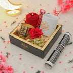 Gift set with red roses, a mug, and a pen on a decorative surface with flowers.