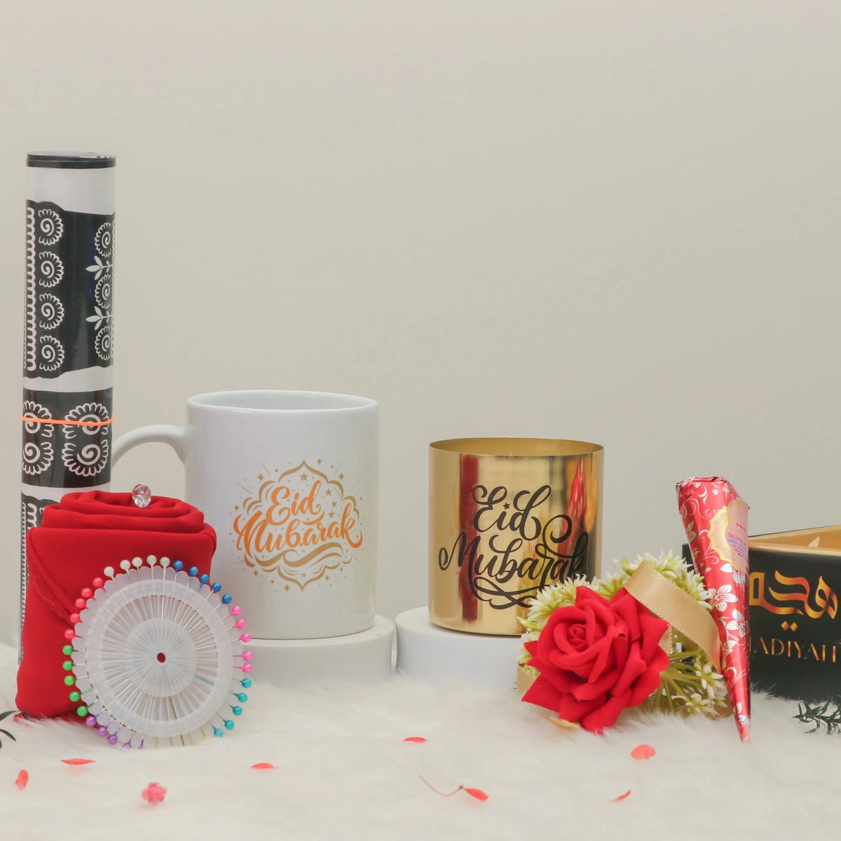 Afiyah Eid Hamper - Eid Gift Hamper for Women displayed with white mug, gold candle holder, red hijab, rose, and henna cone on white background.