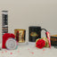 Afiyah Eid Hamper - Eid Gift Hamper for Women shown with black mug, gold candle holder, red hijab, rose, and henna cone for festive gifting.