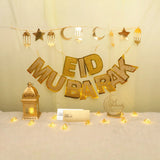 Eid Grand Celebration Decor Set featuring gold Eid Mubarak banner, lantern, moon and star garland, envelopes, and warm string lights.