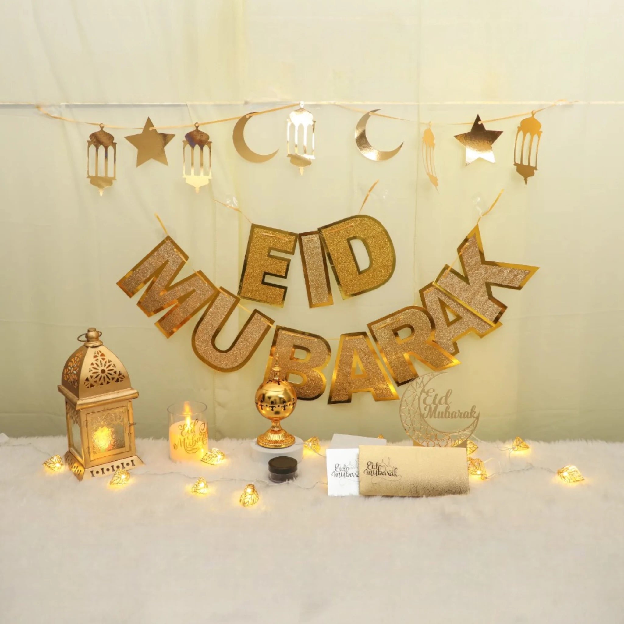 Royal Eid Glow Decor Set featuring gold 'Eid Mubarak' banner, lantern, moon and star garlands, lights, and Eidi envelopes for festive home decor. Main image