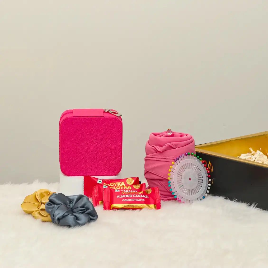 Contents of Shukr Eid Hamper displayed: pink jewelry box, hijab, almond caramel treats, scrunchies, and pinwheel, ideal Eid gift for women.