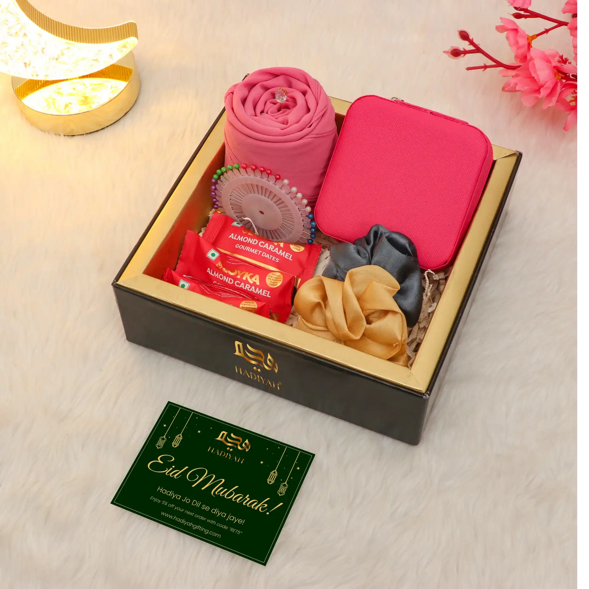 Gift box with pink items, a card, and decorative elements on a light background