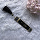 Decorative black bookmark with tassel on a fluffy white surface with pink flowers.