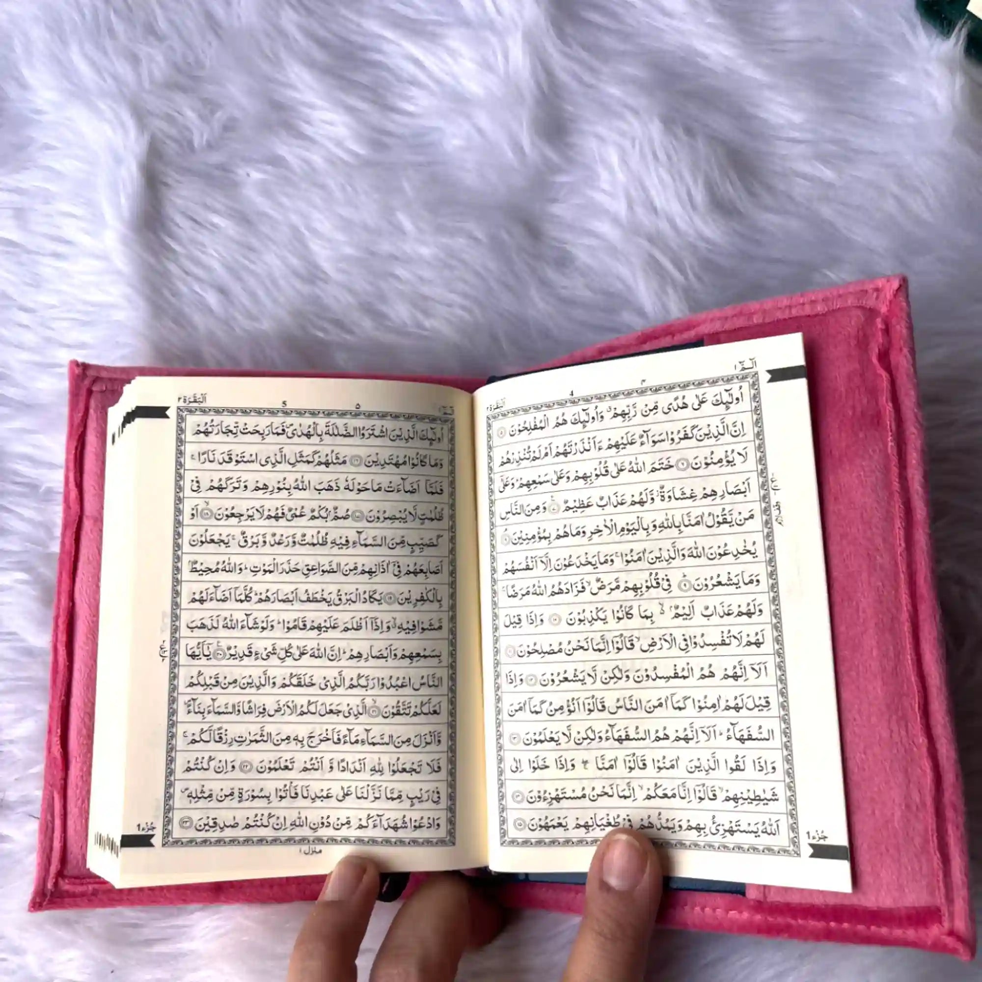 Open book with text held by a hand on a fluffy white surface Main image