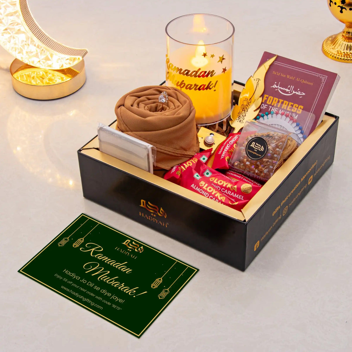 Gift set with candles, snacks, and a card on a white surface