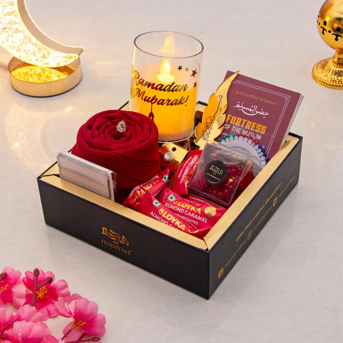 Gift box with red rose, candles, and books on a light background