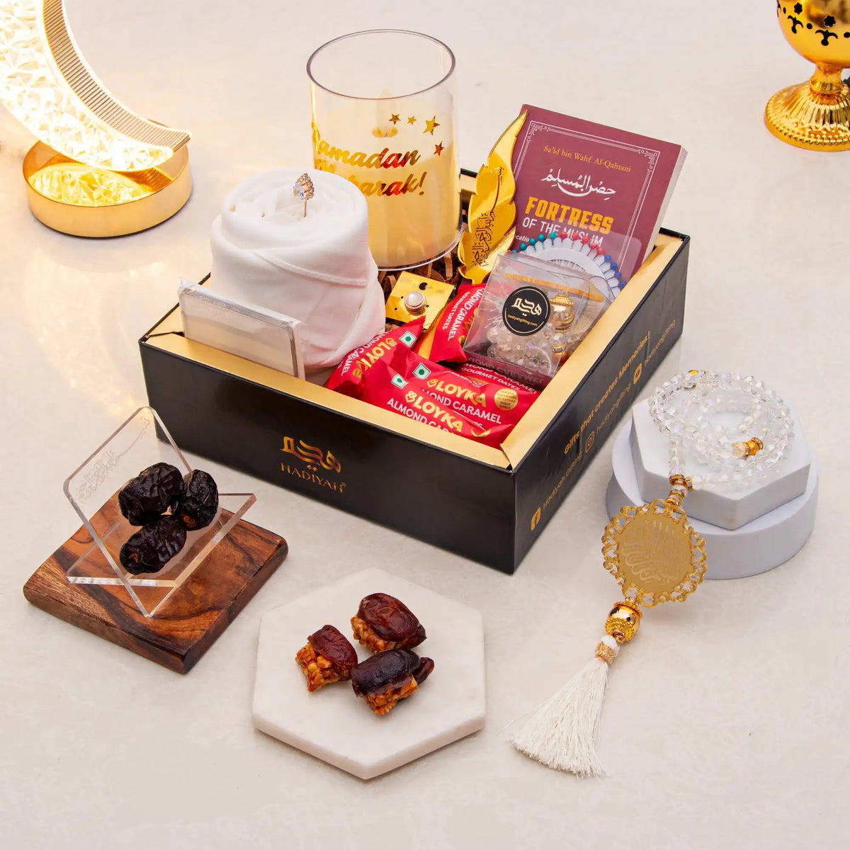 Gourmet gift box with snacks, dates, and a candle on a decorative surface.