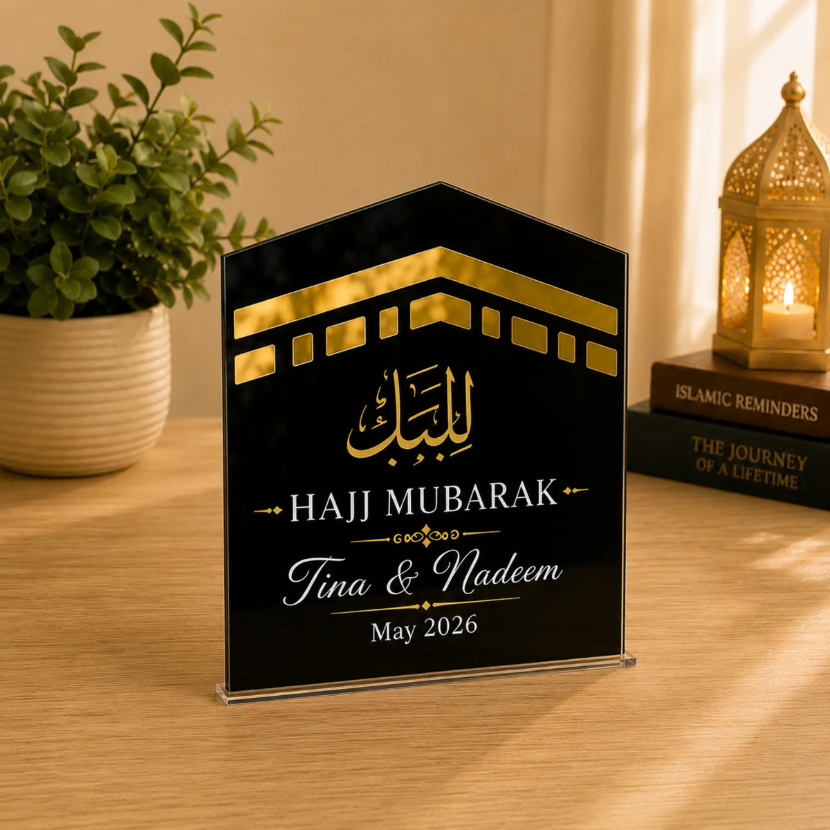 Hajj Mubarak plaque with gold and white text on a wooden surface with decor items.