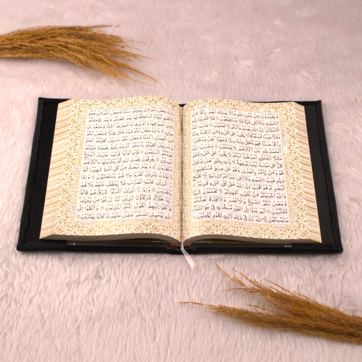 Open velvet Quran from the Black Sequence Rehal Hamper - Luxury Quran Gift Set, displayed on a soft fur surface with decorative grass accents.