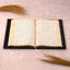 Open velvet Quran from the Black Sequence Rehal Hamper - Luxury Quran Gift Set, displayed on a soft fur surface with decorative grass accents.