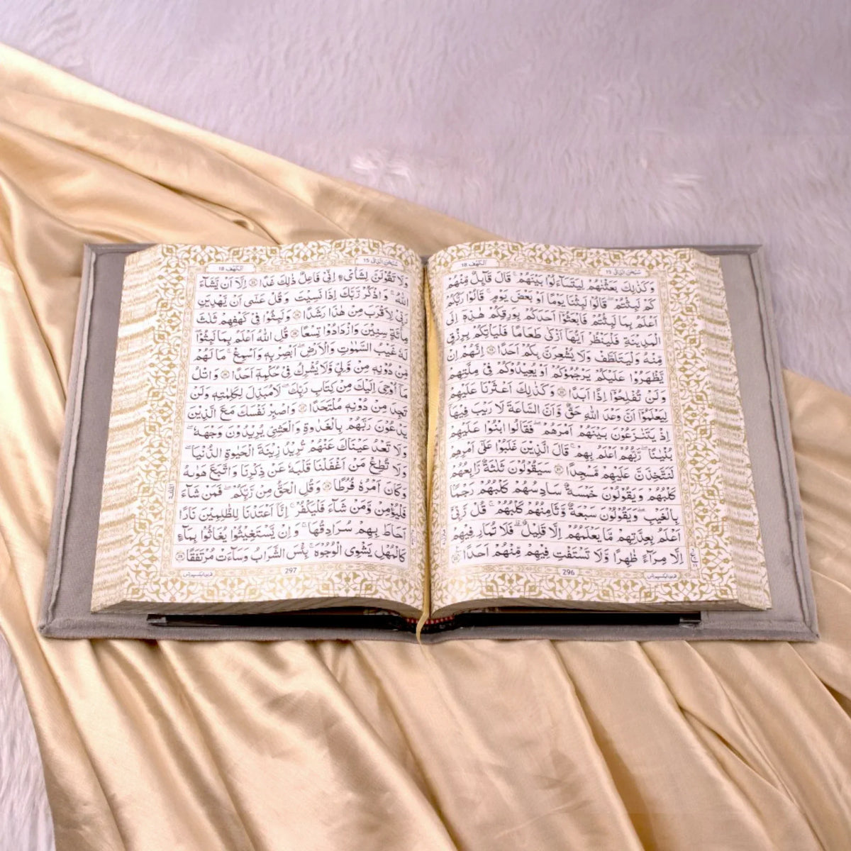 Open Holy Quran with ornate golden border and grey velvet cover from the Velvet Quran Rehal Hamper. Luxurious Islamic gift for special occasions.