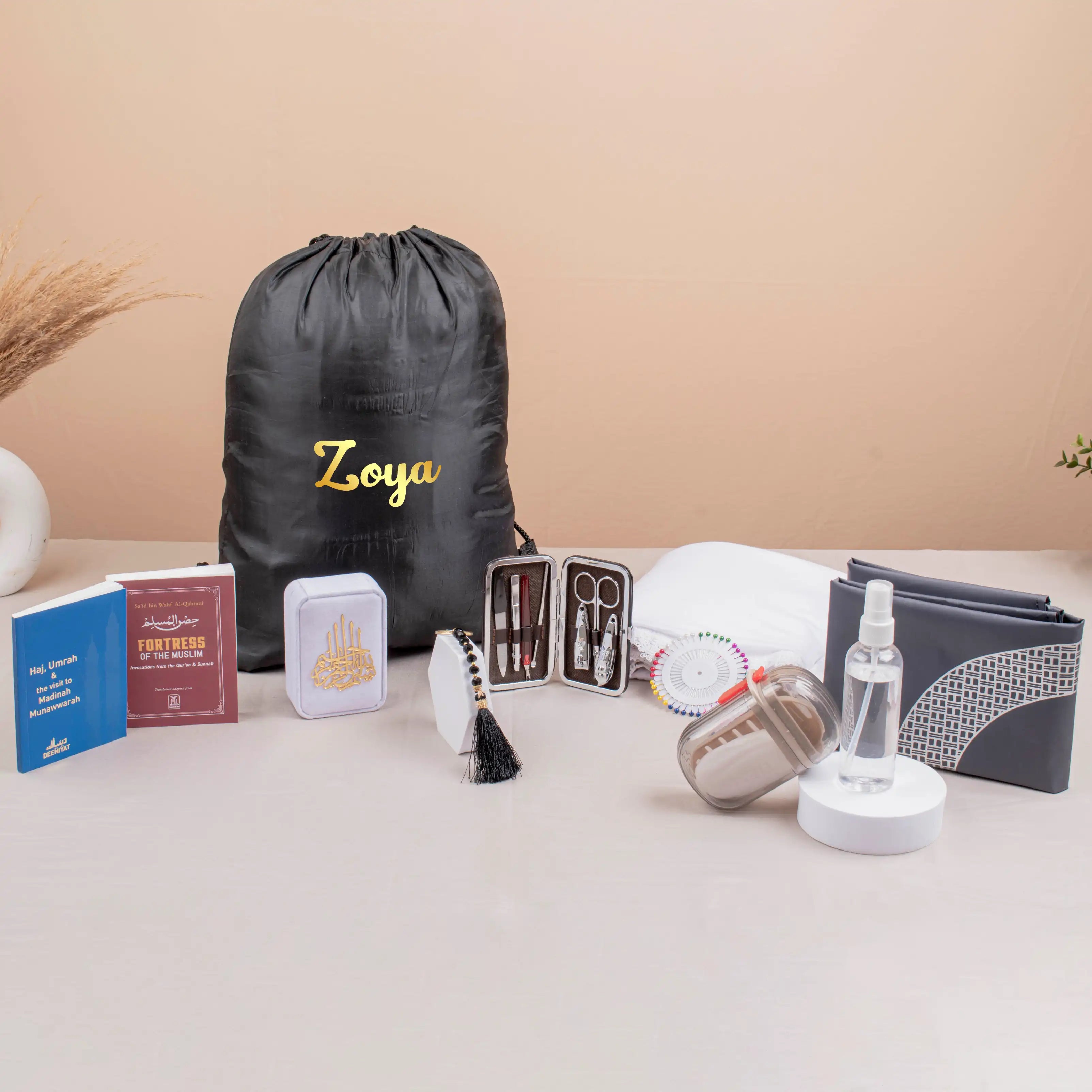 Labbaik Nisaa Women's Safar Essentials Kit featuring hijab, prayer mat, books, and grooming tools in a personalized drawstring bag for Hajj or Umrah. Main image