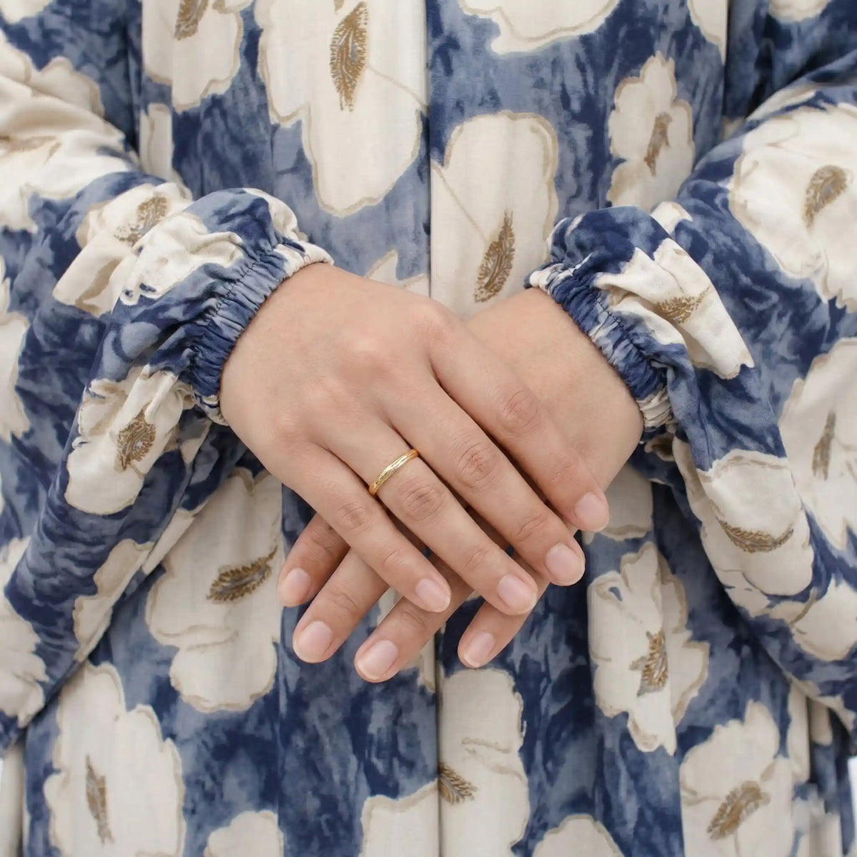 Woman's hand with gold ring on floral prayer dress sleeve
