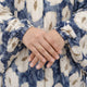 Woman's hand with gold ring on floral prayer dress sleeve
