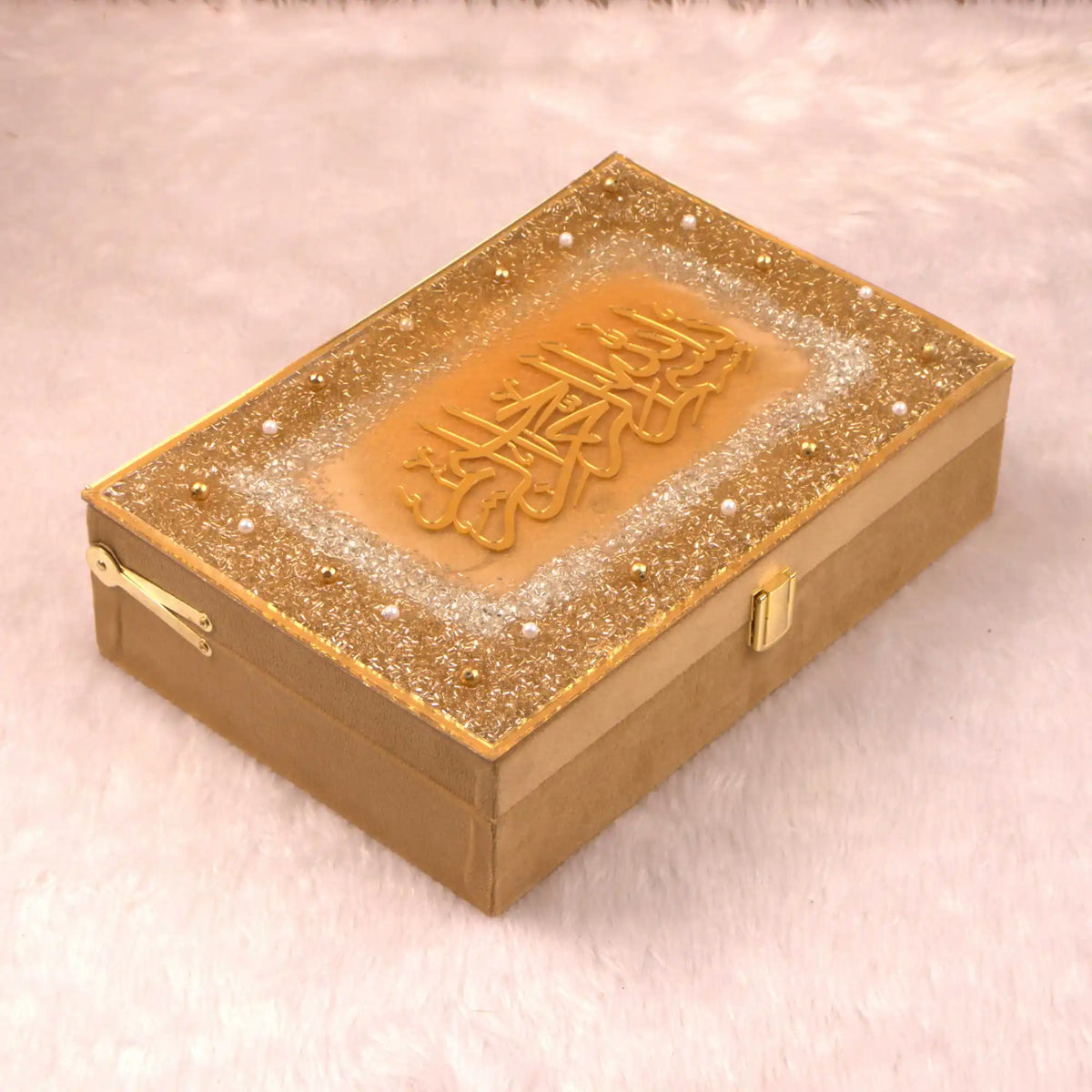 Decorative gold box with intricate design on a light pink background