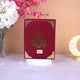 Red book with gold design on a white surface with flowers and a decorative moon lamp in the background
