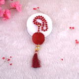 Decorative red tassel with beads on a white plate against a pink floral background