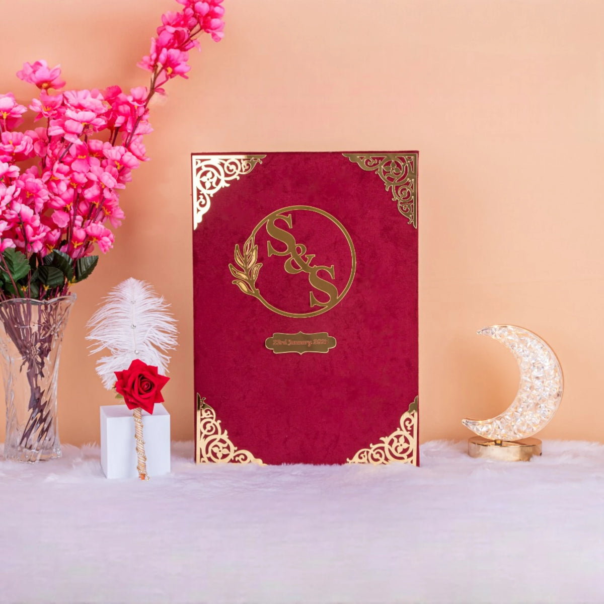 Red velvet Whispering Flowers Nikah Nama with gold embossed initials and ornate Islamic design, a luxurious wedding gift option.