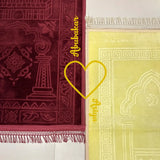 Two prayer mats, one red and one yellow with intricate patterns, on a white background.