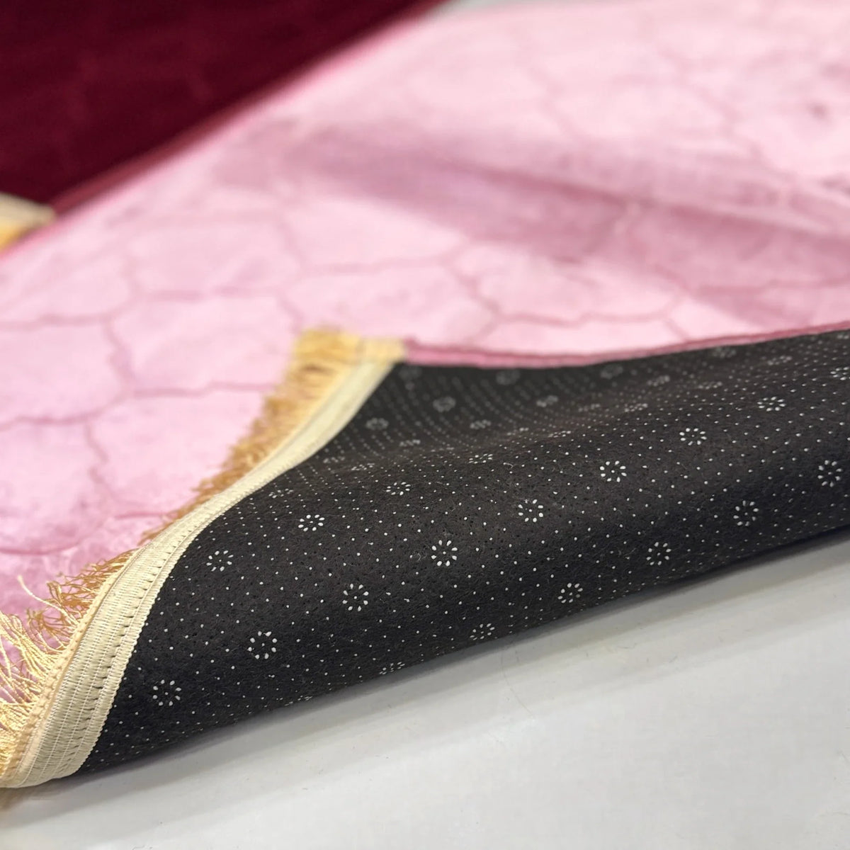 Underside of pink Janamaz from Couple Dome Prayer Mat Set, showing anti-slip backing and golden fringe detail for added comfort.