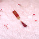 Decorative red and gold bookmark with tassel on a pink textured background