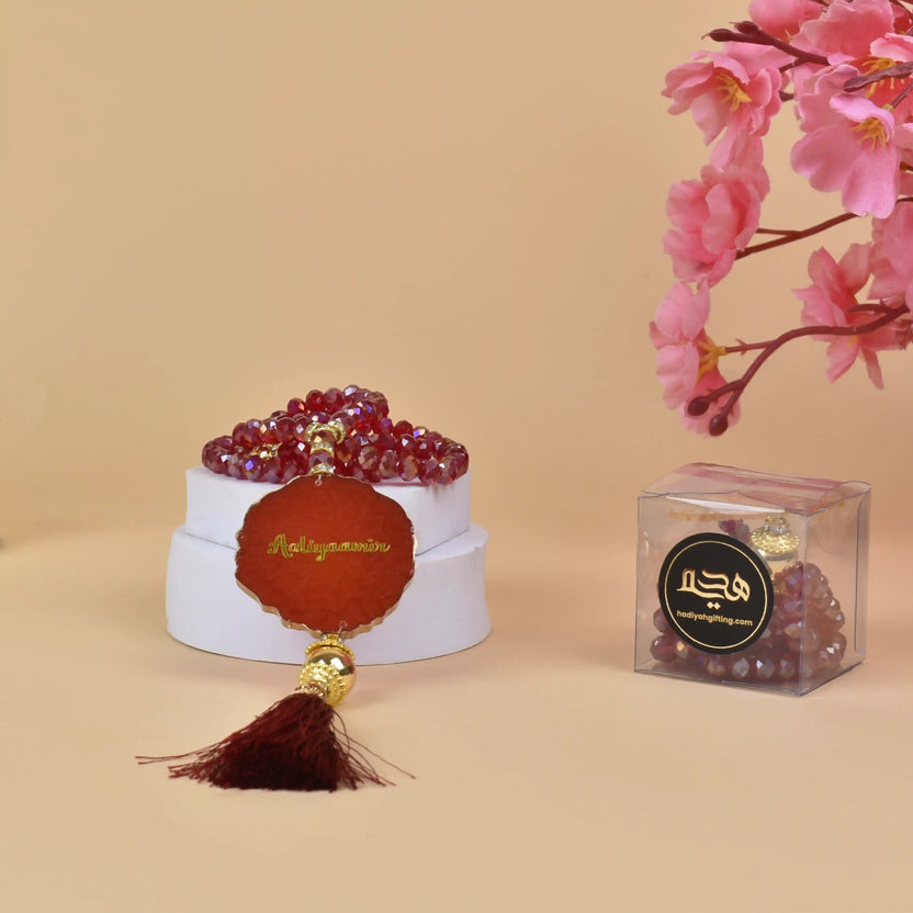 Red crystal tasbeeh with engraved name 'Abdulquddus' in gold, paired with a dark red tassel. Unique custom Islamic gift for ceremonies. Main image