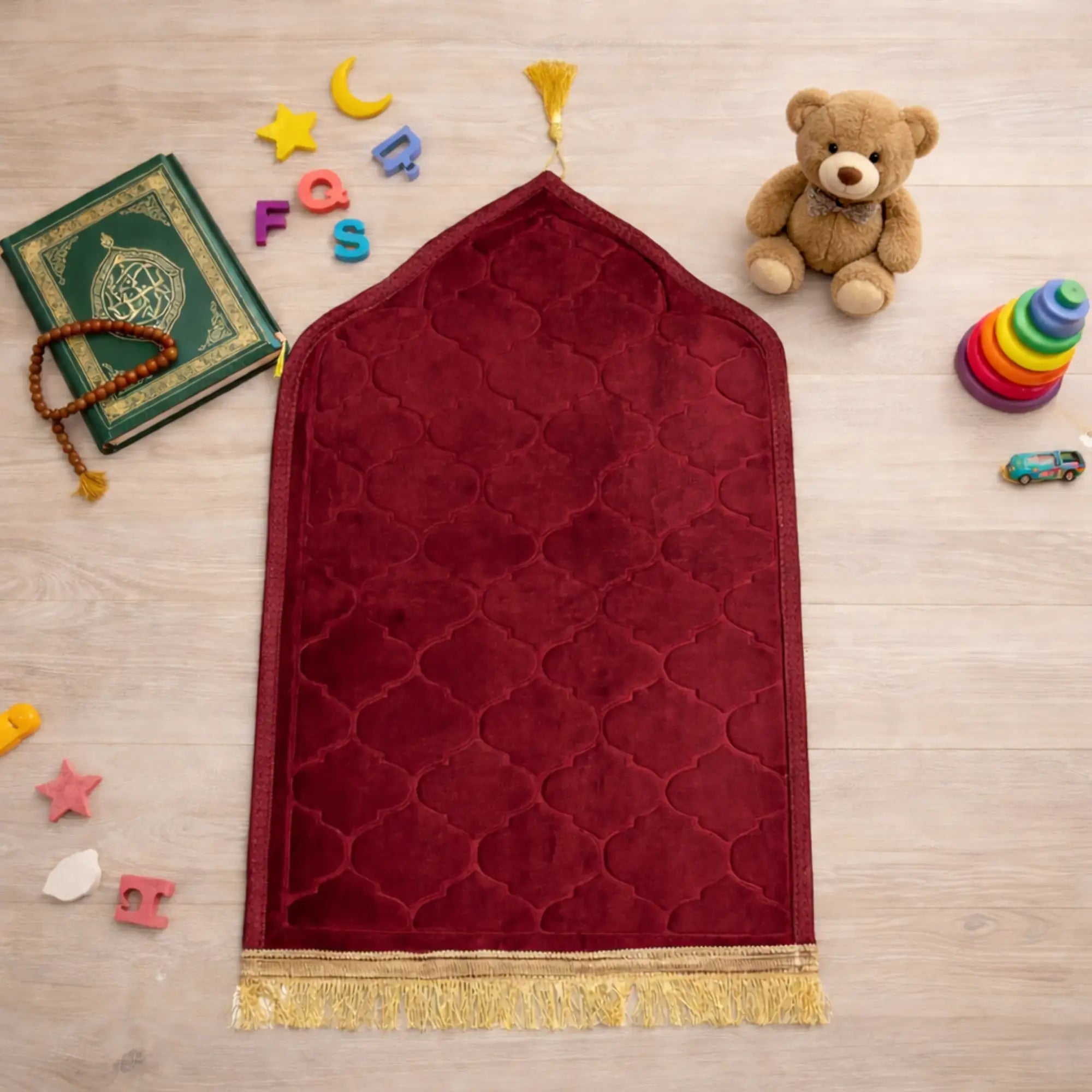 Maroon Kids Dome Janamaz - Kids Dome Prayer Rug surrounded by toys and Islamic items. Soft, foldable design perfect for children.