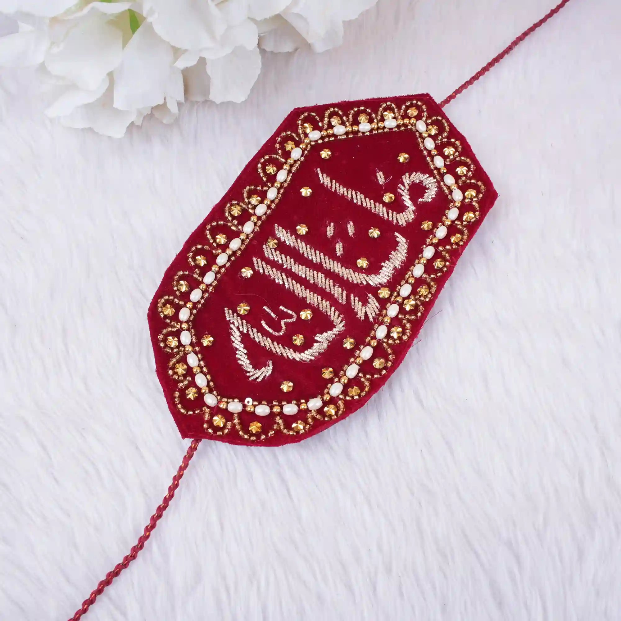 Decorative red and gold embroidered patch on a white fabric background