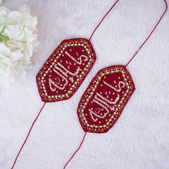 Two red embroidered pieces with gold thread on a white fabric background.