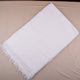 White towel with fringes on a beige surface