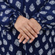 Close-up of a hand wearing a gold ring on a navy blue fabric with white patterns.
