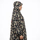 Person wearing a patterned hijab and dress on a white background