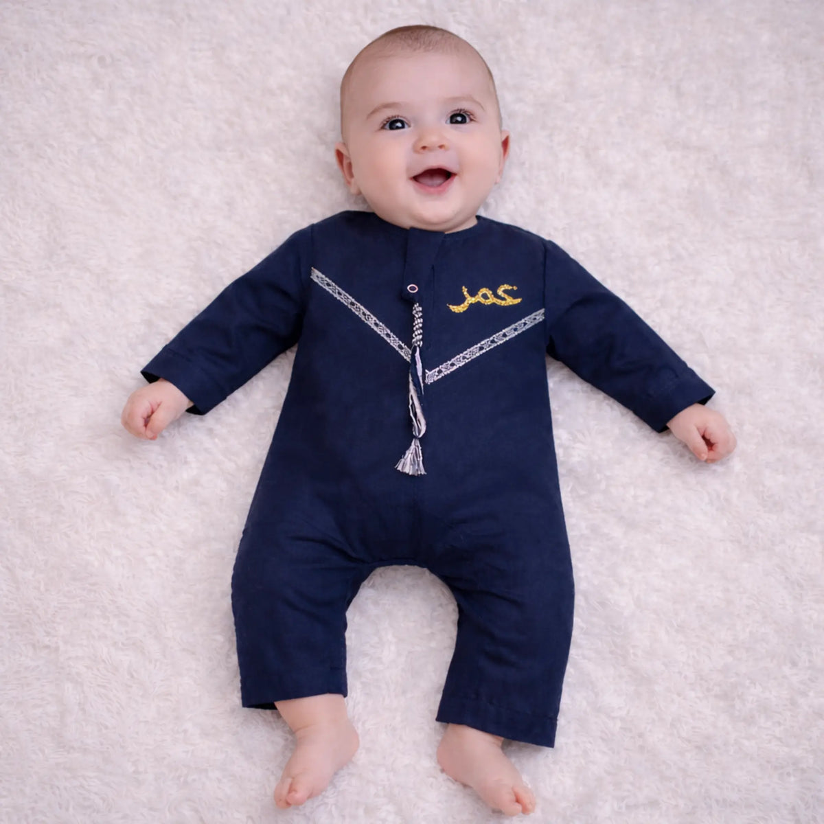 Baby boy in navy blue traditional Islamic outfit on soft white background