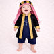 Baby boy in traditional black and gold Islamic outfit with red and white keffiyeh, standing on white textured background