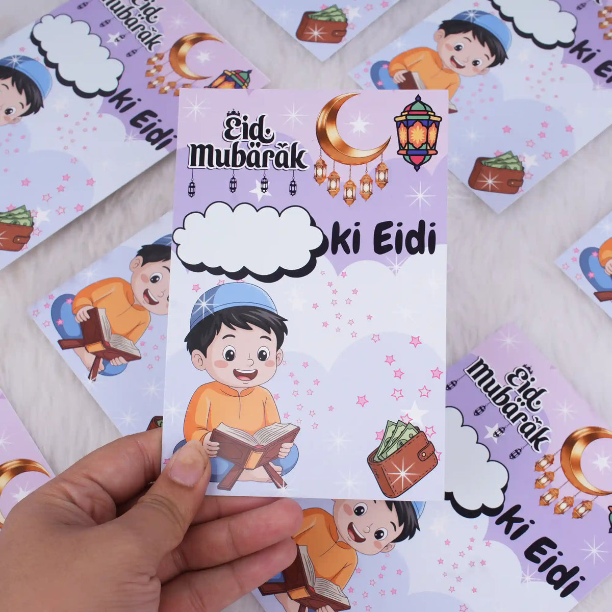 A hand holding a purple premium Eidi card for boys, highlighting the blank cloud space for personalizing the recipient's name.