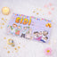 A single light purple Eidi gift envelope featuring the word 'EIDI' in bold yellow letters and cartoon illustrations of a Muslim family celebrating. The envelope is displayed on a soft white faux fur surface, styled with a lit tea light candle, scattered golden star confetti, a crescent moon charm, and a pink flower.